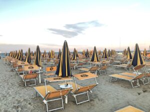 Spiaggia di Rimini affollata con ombrelloni, evidenziando gli errori comuni dei turisti al mare.