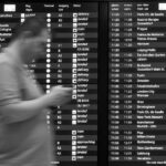 Passeggeri al check-in in aeroporto, preoccupati per possibili errori che potrebbero far perdere il volo.