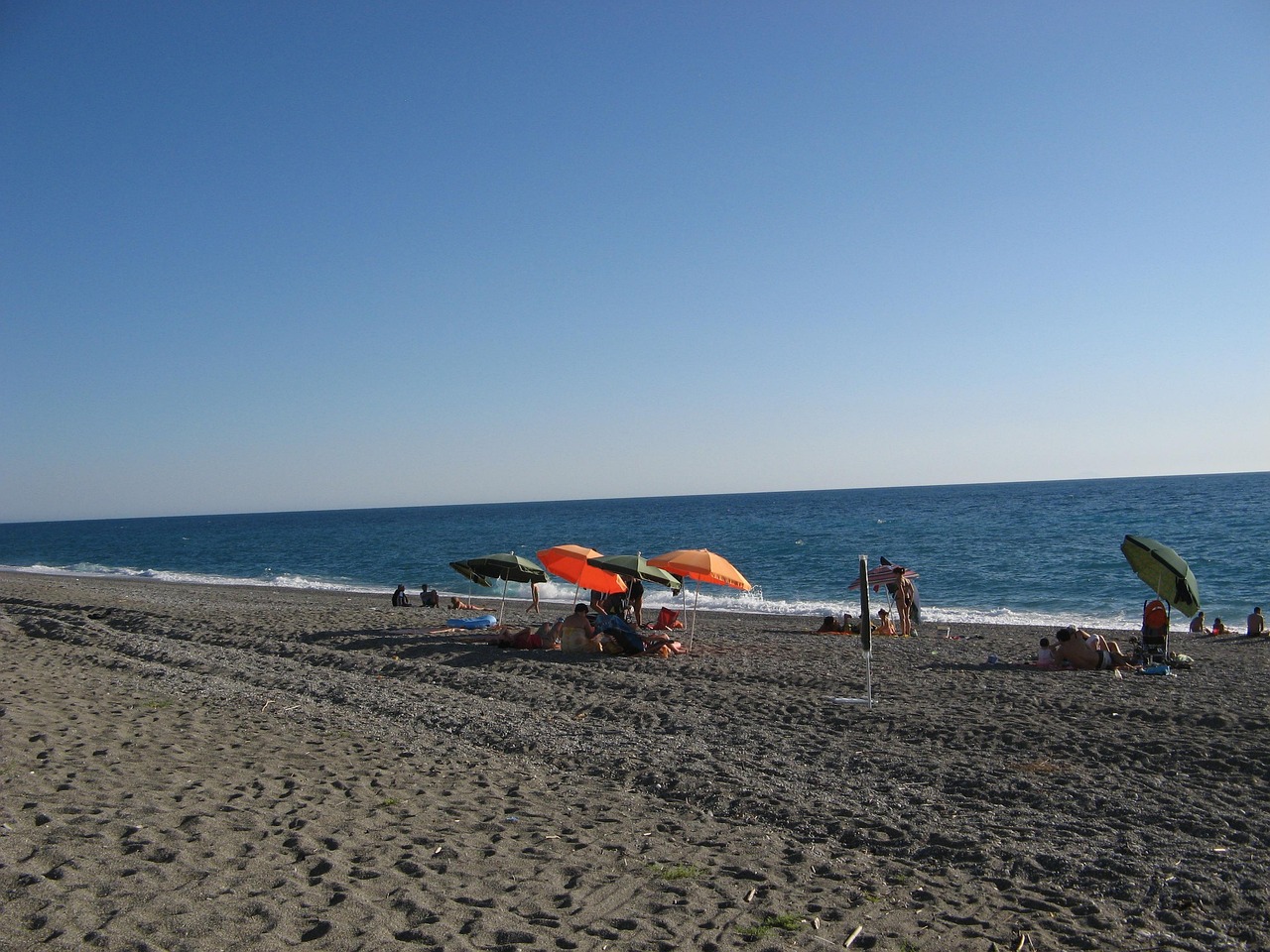 Spiaggia pulita con sabbia dorata e acque cristalline lungo la Riviera Ligure.