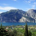 Vista panoramica del borgo di Riva del Garda con montagne sullo sfondo, perfetta per un'estate in montagna.