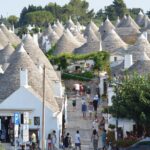 Piatti tipici di Alberobello serviti in un ristorante, con trulli sullo sfondo.