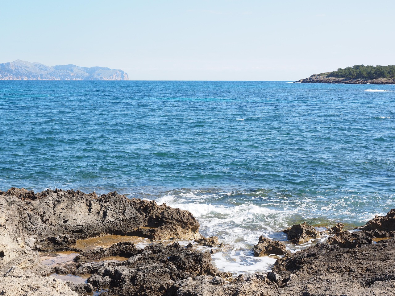Spiaggia affollata a Maiorca con ombrelloni e bagnanti sotto il sole.