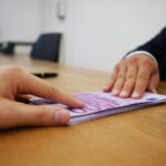 Giocatori di "Affari Tuoi" con banconote e premi in un momento di gioco emozionante.