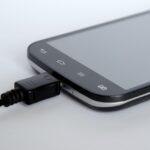 Caricabatterie per smartphone collegato a una presa elettrica durante la notte.